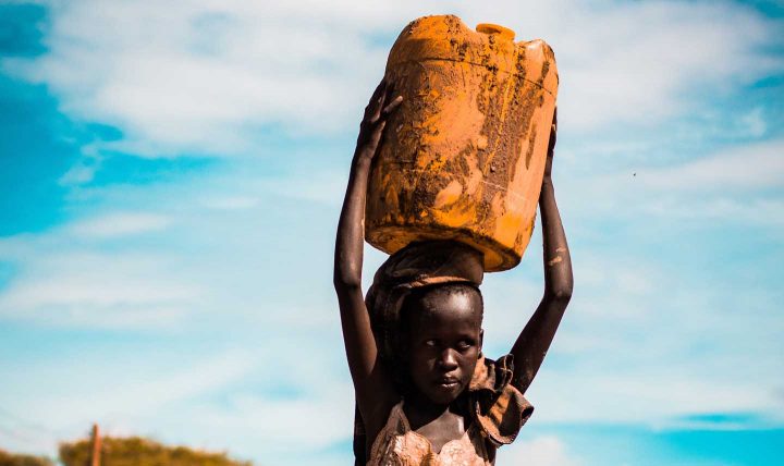 Uma menina africana carregando água para casa