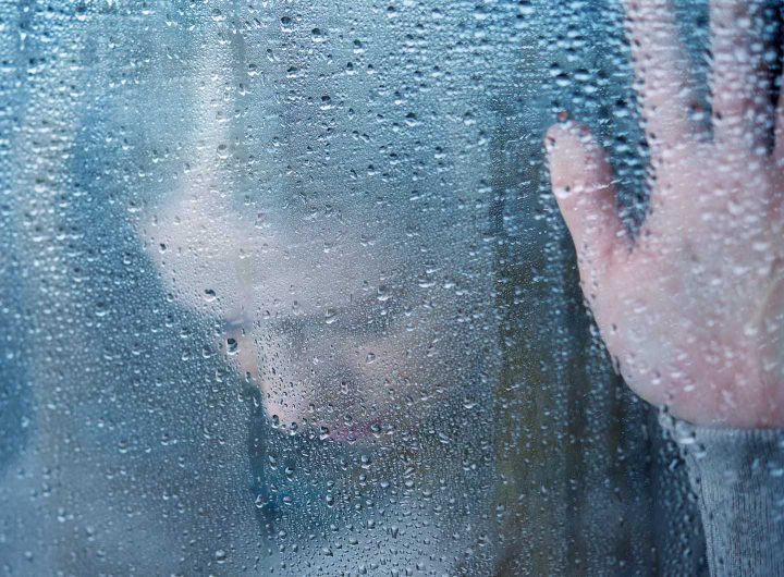 Pessoa depressiva numa janela chuvoso